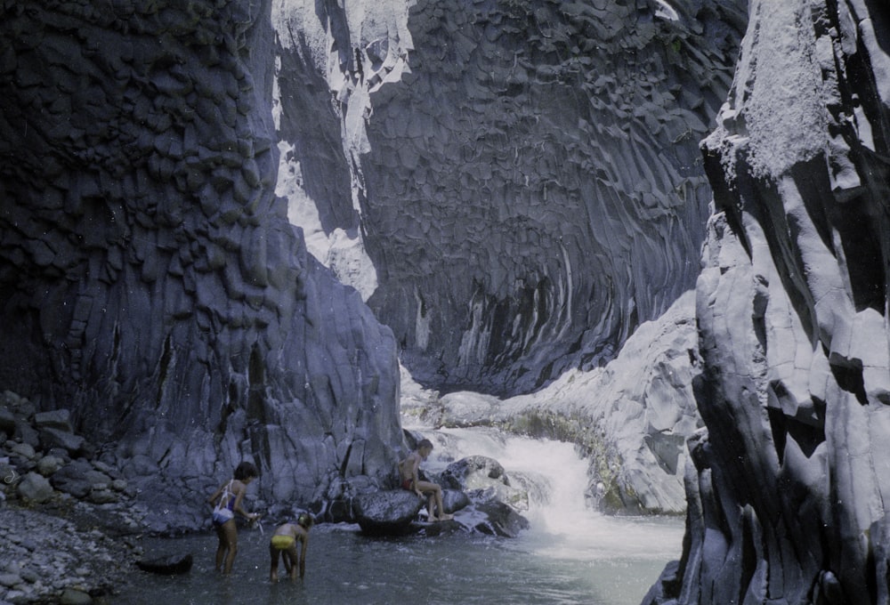 people in water near gray rock formation during daytime