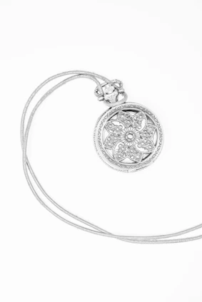silver round pendant with white background