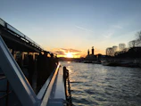 Sunset silhouette of a fuel tanker crossing a bridge over a wide river.