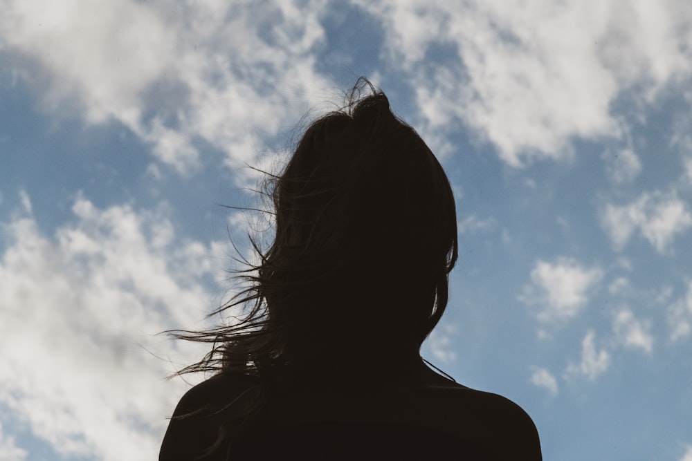 silhouette di donna sotto cielo blu e nuvole bianche durante il giorno