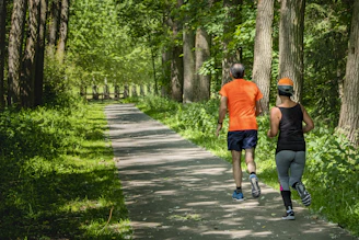 man in orange t-shirt and gray pants with blue shoes walking on pathway