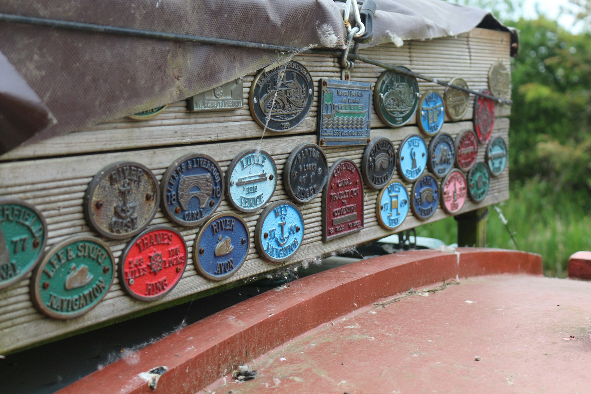 A variety of colorful metal plaques arranged neatly on a workshop table, showcasing different fonts and styles.
