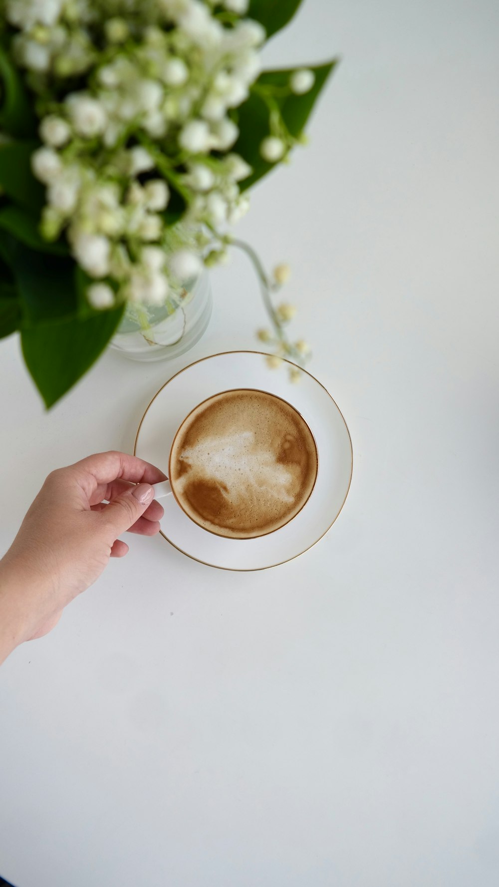 person holding white ceramic mug with brown liquid