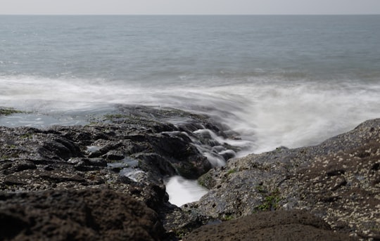 ocean waves crashing on rocky shore during daytime in Harihareshwar India