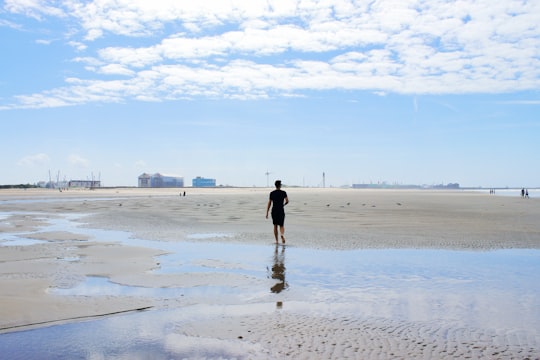 man in black shirt walking on beach during daytime in Dunkerque France