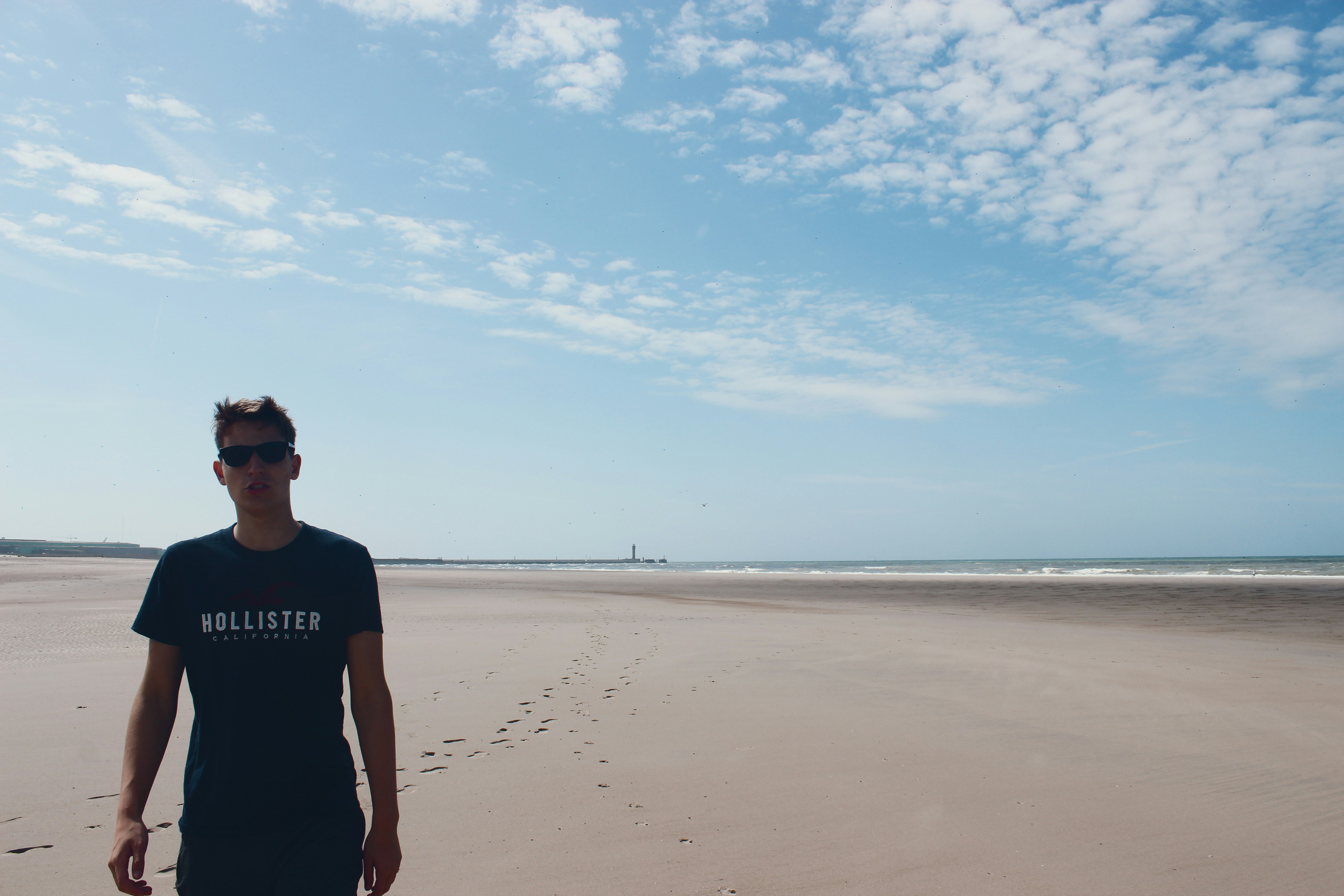 man in black crew neck t-shirt standing on brown sand during daytime