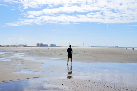 man in black shirt walking on beach during daytime in Dunkerque France