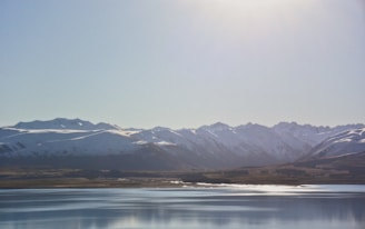Snow-capped mountains framing a serene lake in Kyrgyzstan under a clear blue sky.