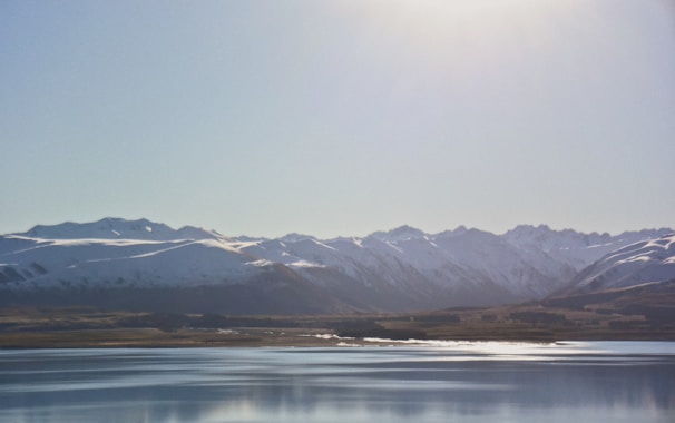 Snow-capped mountains framing a serene lake in Kyrgyzstan under a clear blue sky.