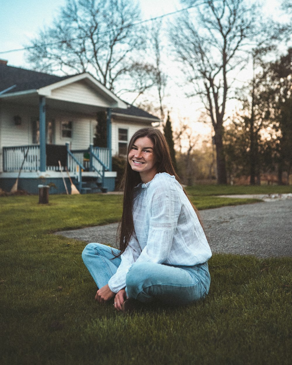 woman in white long sleeve shirt and blue denim jeans sitting on green grass field during