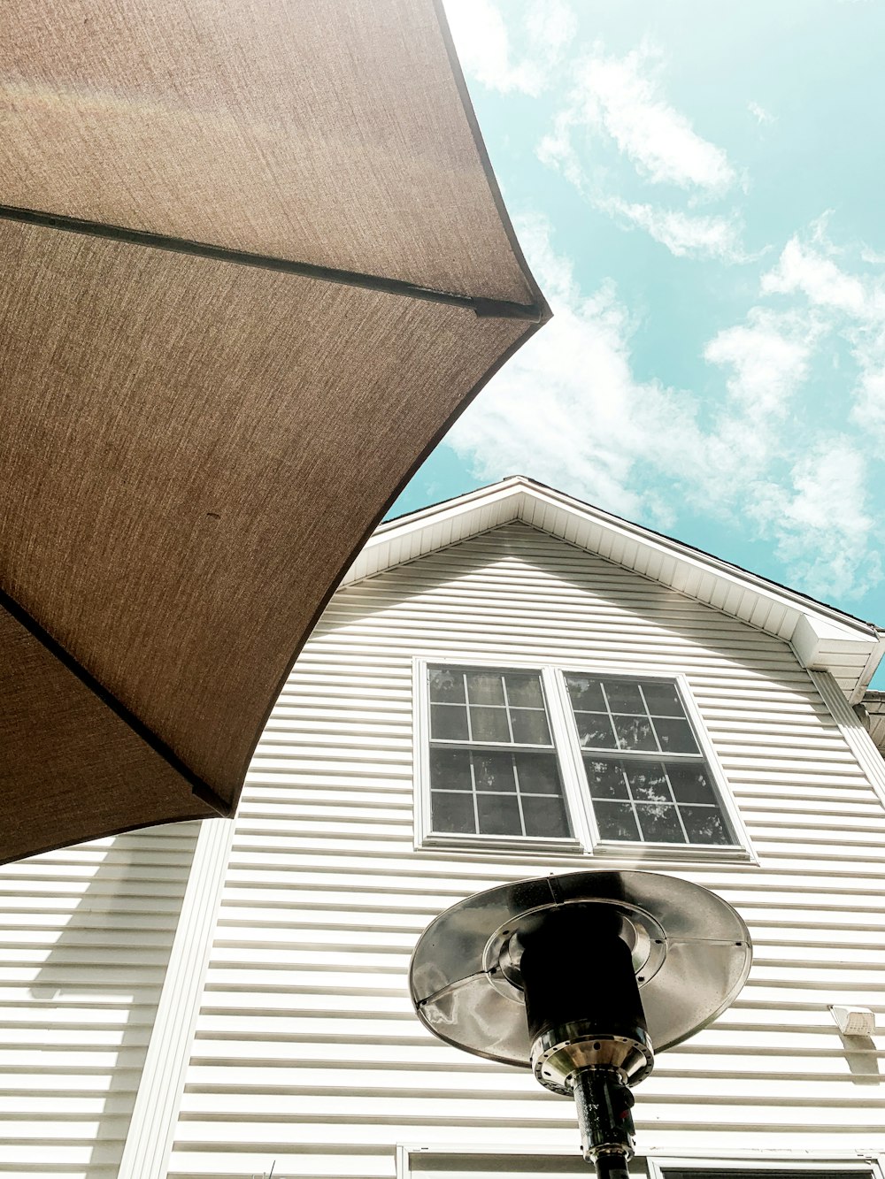 brown umbrella near white wooden house during daytime
