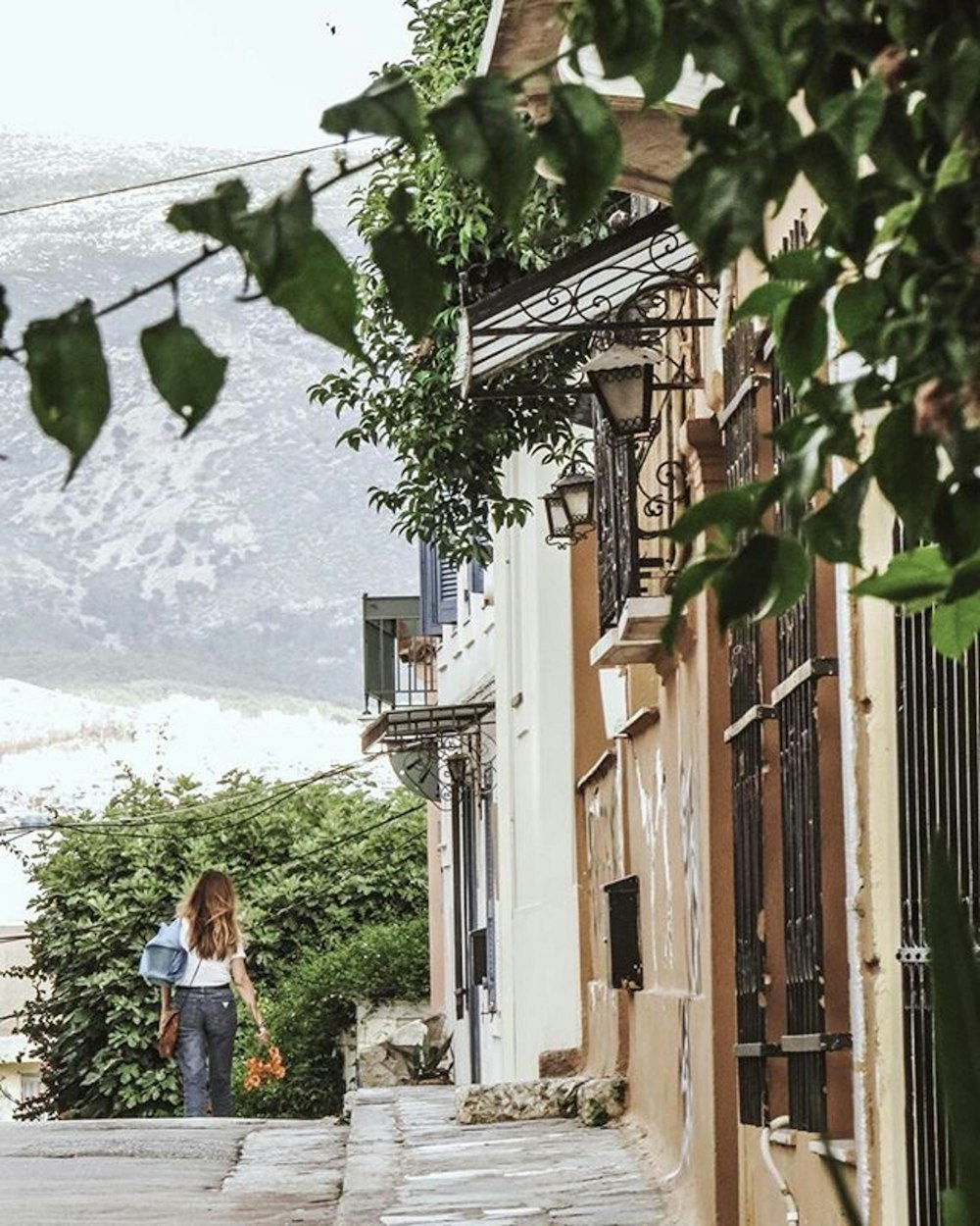 woman in white shirt and blue denim jeans standing on brown wooden fence during daytime