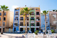 Balcony view of a vibrant street in Ibiza with colorful buildings and palm trees.