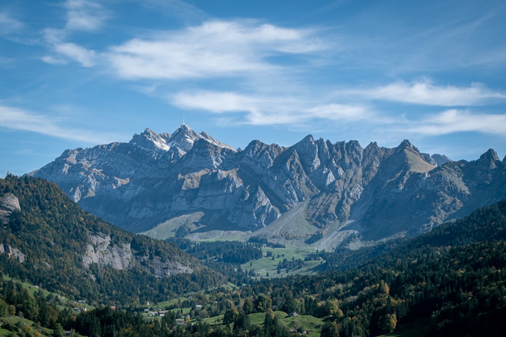 green trees and mountains under white clouds and blue sky during daytime