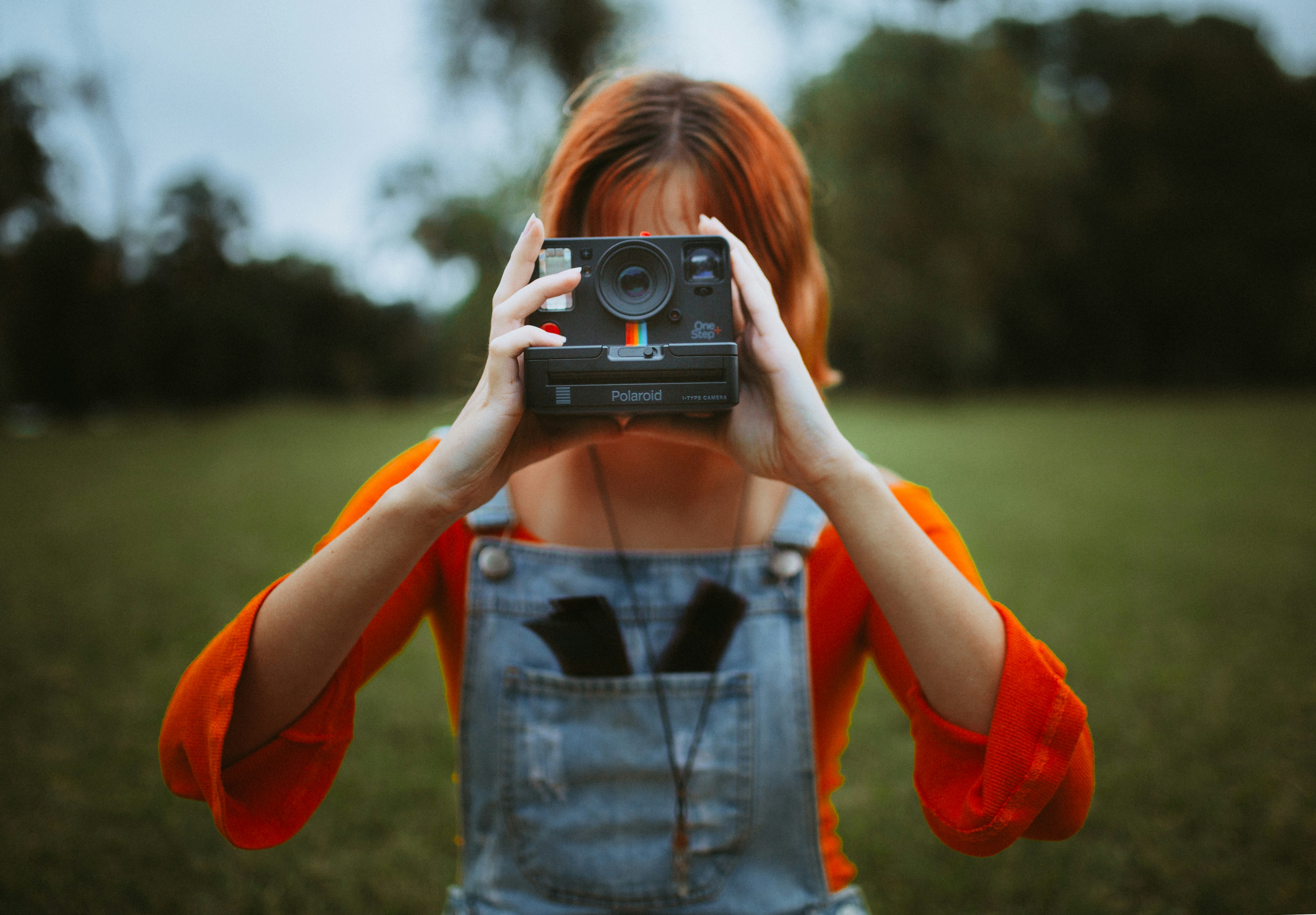 Frau im roten Langarmhemd mit schwarzer und silberner Kamera