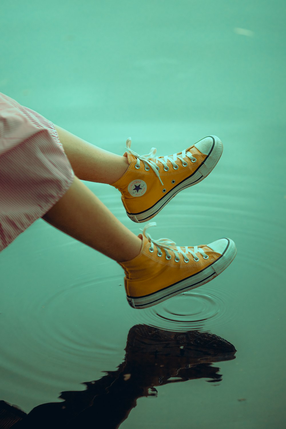 person wearing pink pants and yellow converse all star high top sneakers