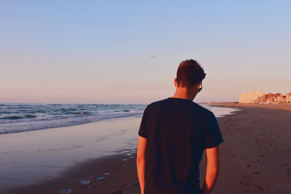 man in black crew neck t-shirt standing on beach during daytime