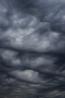 Dark, swirling storm clouds fill the sky, creating an ominous and dramatic atmosphere. The cloud formations are dense and layered, suggesting turbulent weather.