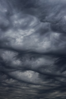 Dark, swirling storm clouds fill the sky, creating an ominous and dramatic atmosphere. The cloud formations are dense and layered, suggesting turbulent weather.