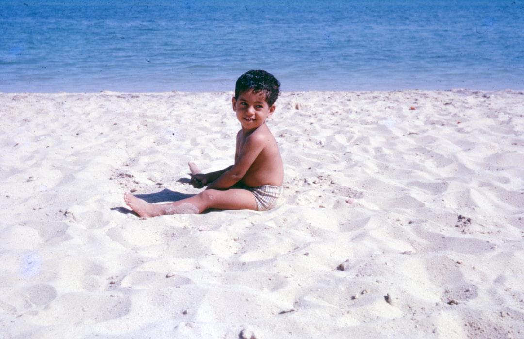 boy sitting on beach shore during daytime