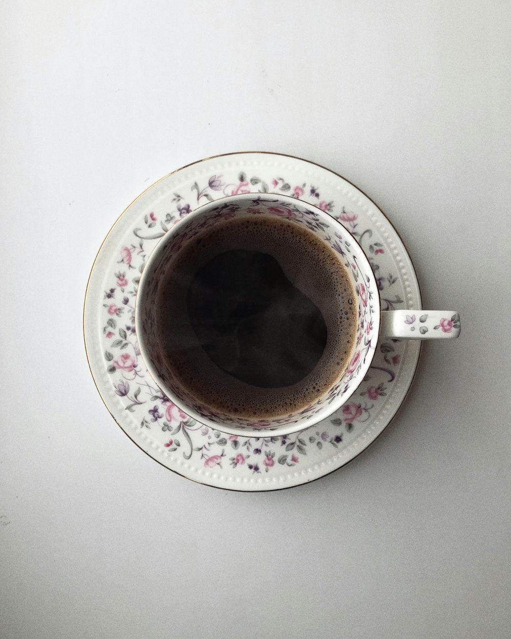 white and pink floral ceramic mug with brown liquid