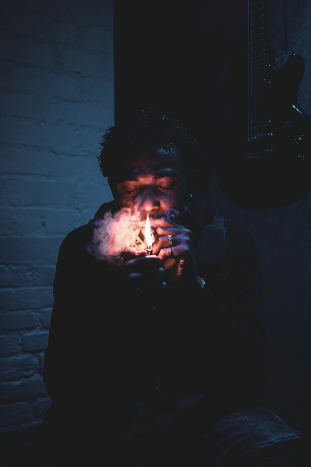 homme fumant une cigarette dans une pièce sombre