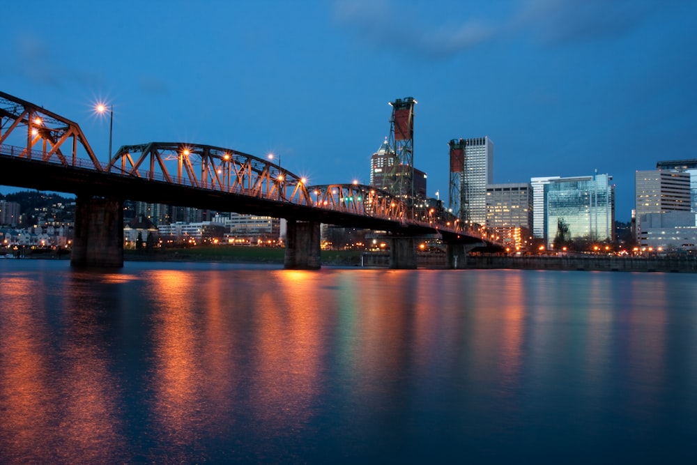 bridge over water near city buildings during night time