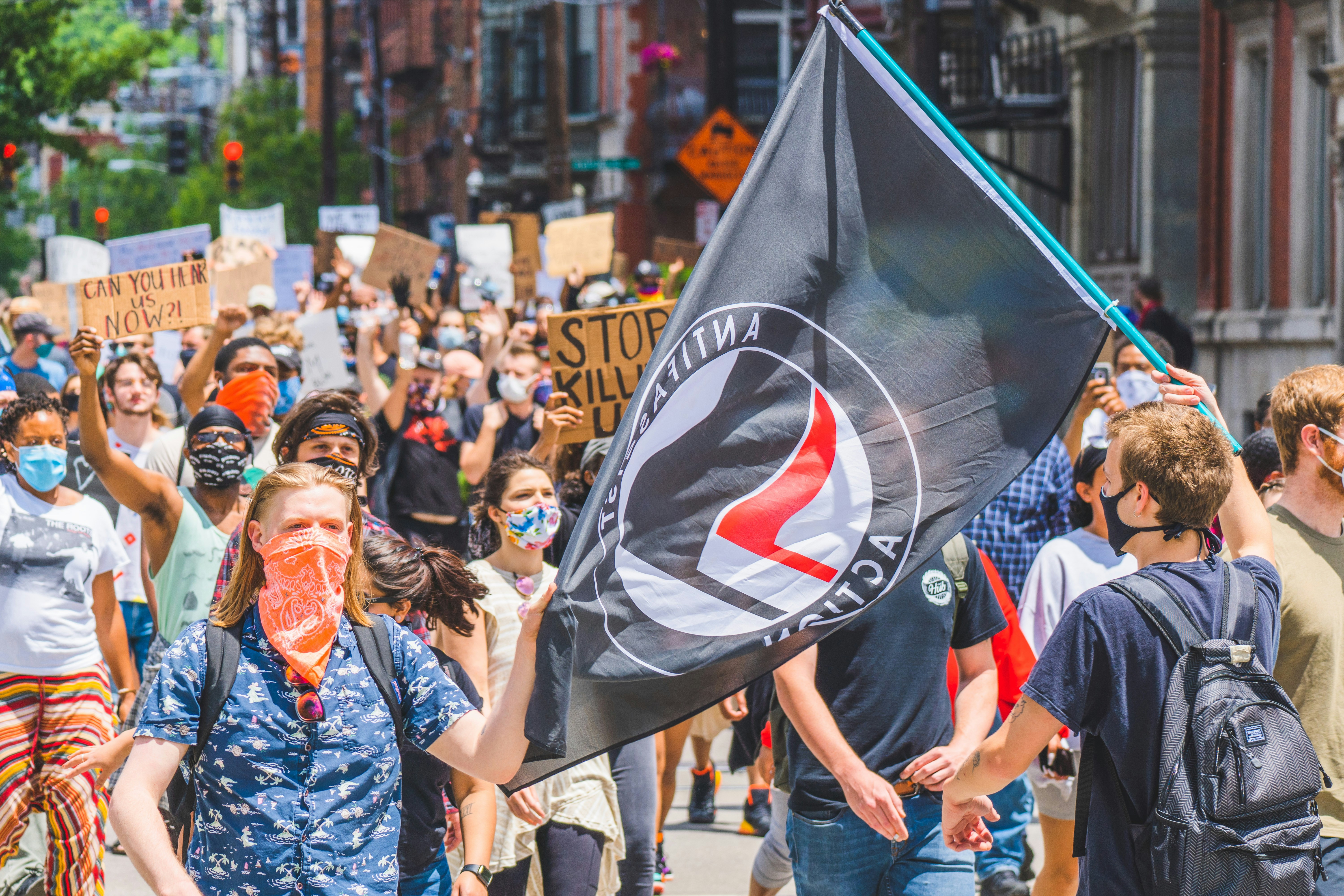 Two protestors holding an Anti-Fascism flag march alongside #BlackLivesMatter activists in Cincinnati