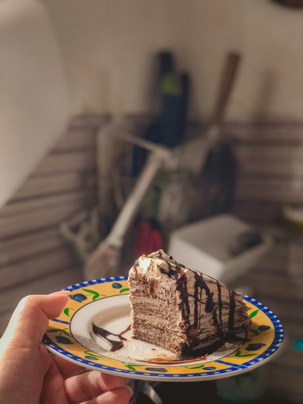 person holding white and blue plate with chocolate cake