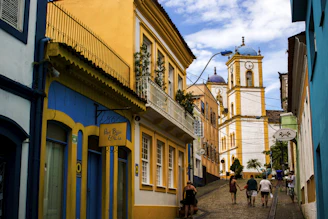 people walking on street near yellow and blue building during daytime