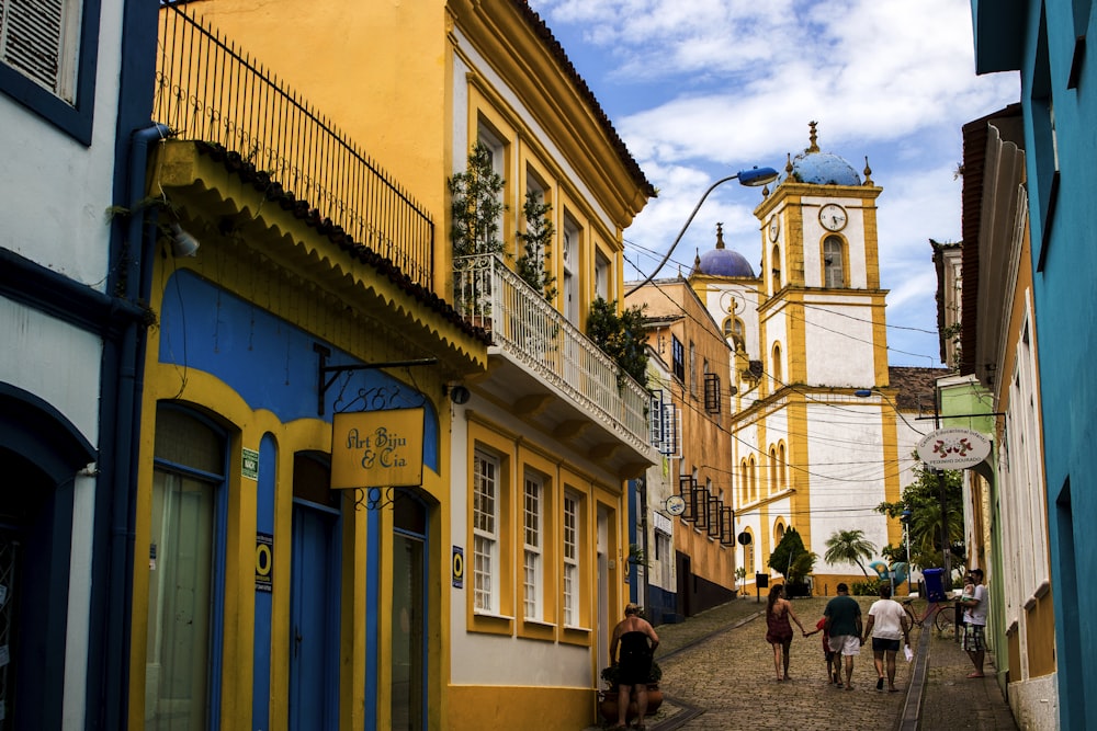 people walking on street near yellow and blue building during daytime