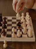 Coach demonstrating a complex chess move on a large wooden board during a class.