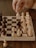 A focused student studying chess moves on a wooden chessboard.