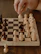 A smiling instructor explaining a chess move to a small group of eager students.