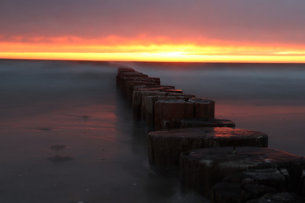 muelle de madera marrón en el mar durante la puesta del sol