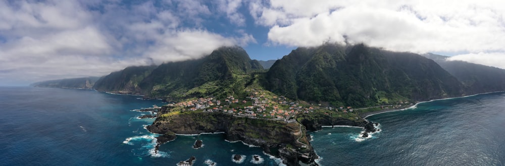 montanha verde ao lado do corpo de água sob o céu azul e nuvens brancas durante o dia