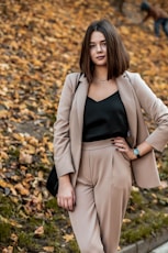 woman in black tank top and beige blazer standing on dried leaves