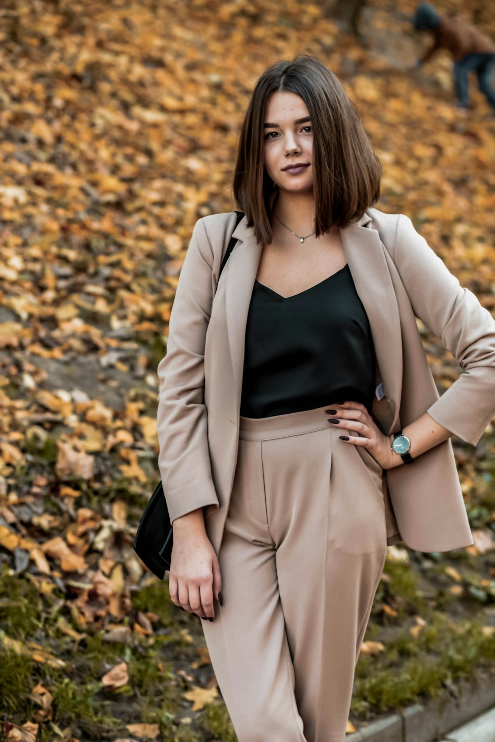 woman in black tank top and beige blazer standing on dried leaves