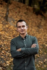 man in black and white striped dress shirt standing near brown leaves during daytime