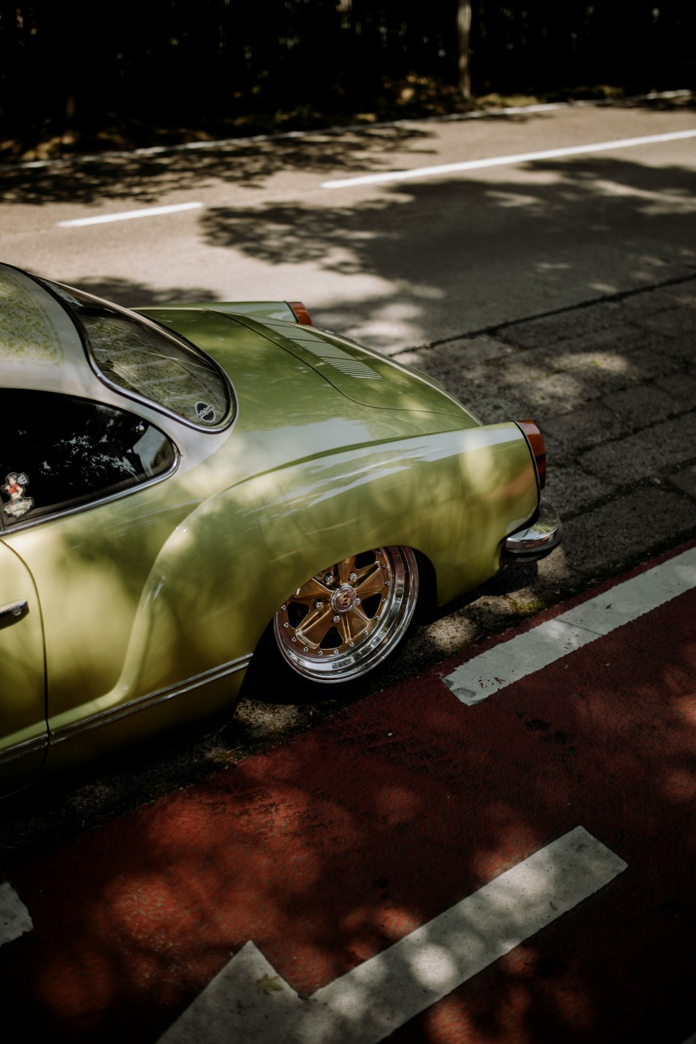 green sedan on gray asphalt road during daytime