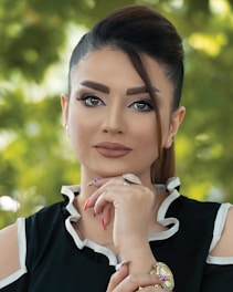 A candid portrait of a confident woman in deep green, soft gold accents highlighting her poised, inviting smile.