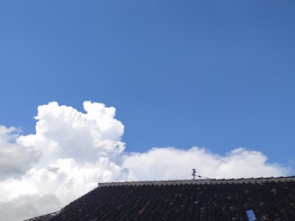 Aerial view of a residential roof with shingles and a clear blue sky.