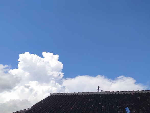 Aerial view of a residential roof with shingles and a clear blue sky.