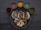 A round black plate contains three tacos filled with grilled meats and vegetables, surrounded by six small bowls of various colored sauces. The tacos are accompanied by grilled onions and slices of zucchini, and the sauces include red, yellow, green, and brown varieties.