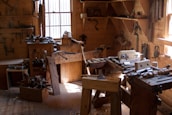 Artisan shaping wood with traditional tools in a bright workshop.