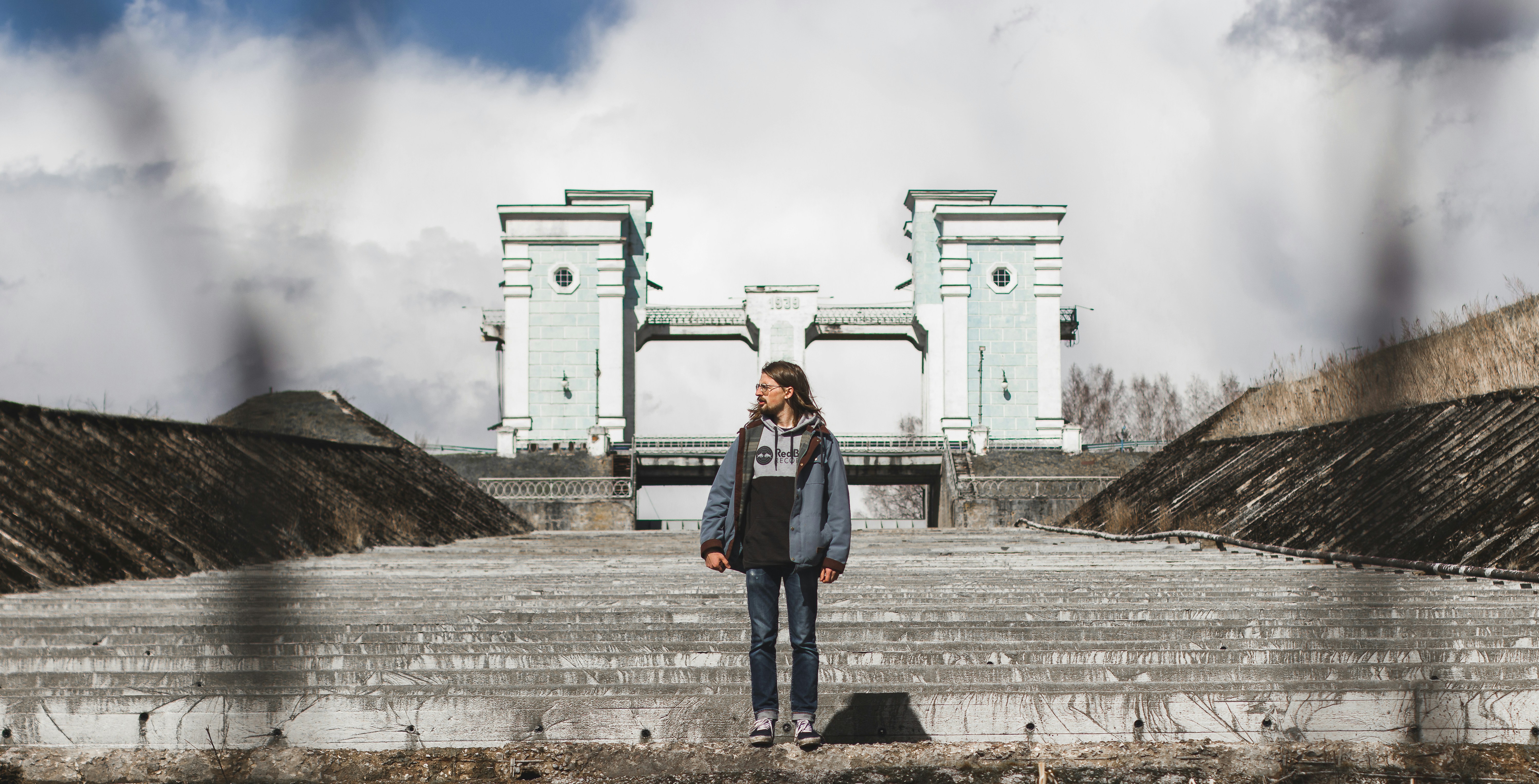 Hombre con chaqueta de mezclilla azul de pie cerca de un edificio de hormigón blanco durante el día