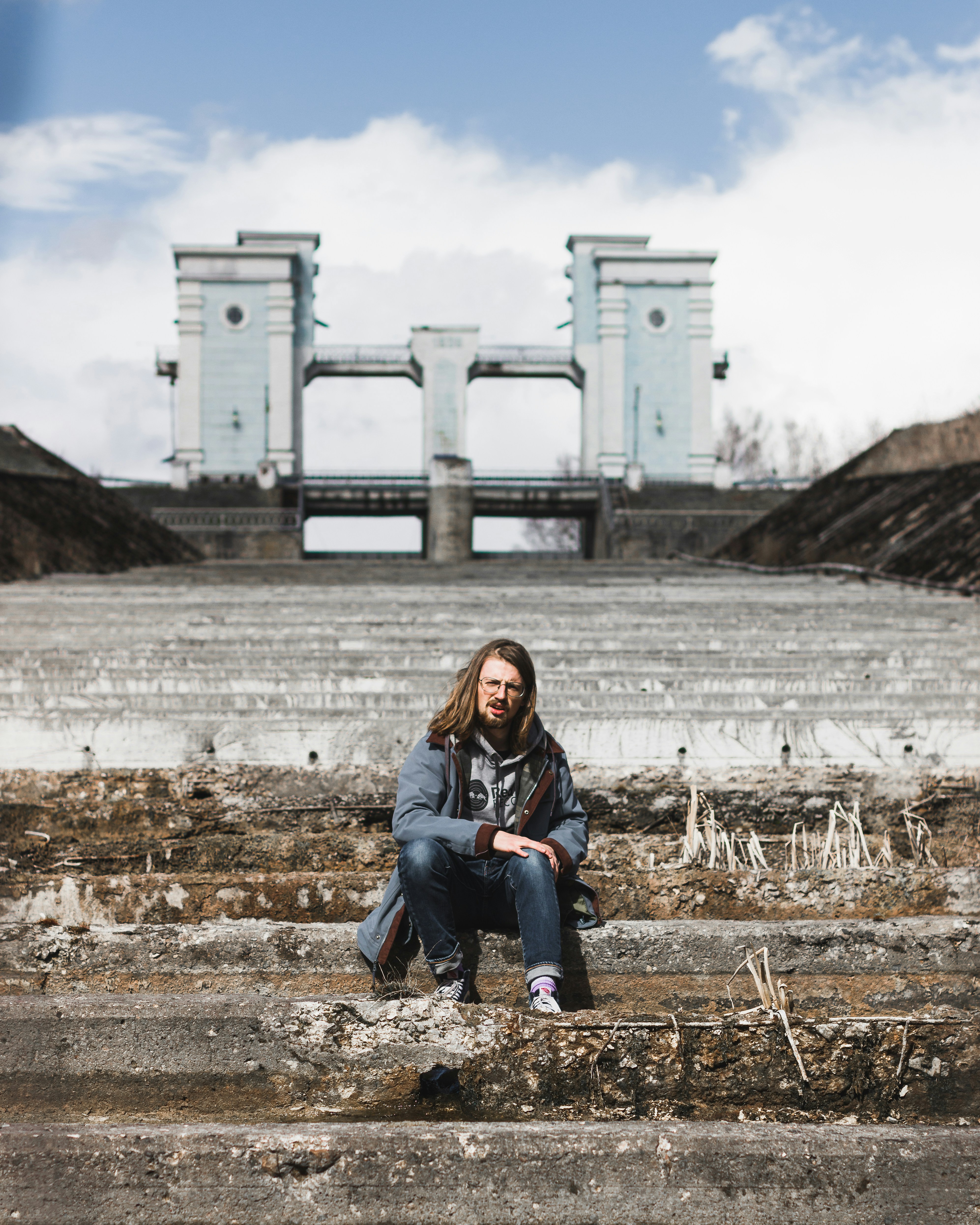 Hombre en chaqueta negra sentado sobre hojas secas marrones durante el día