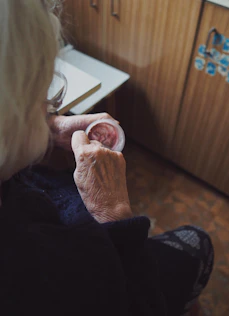 A caring caregiver gently helping an elderly woman with her morning routine in a cozy home setting.
