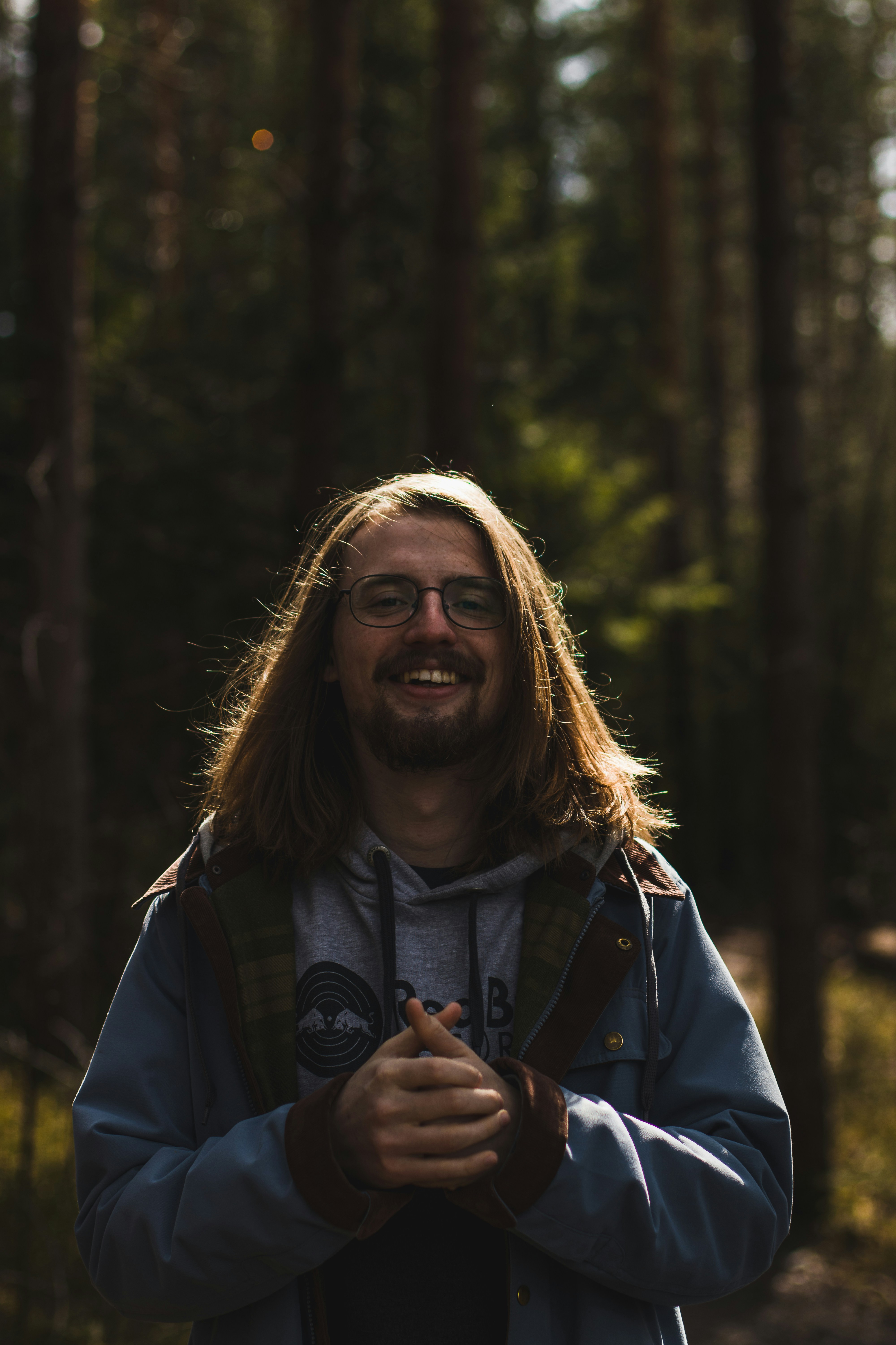 Mujer sonriente en chaqueta negra de pie cerca de los árboles durante el día