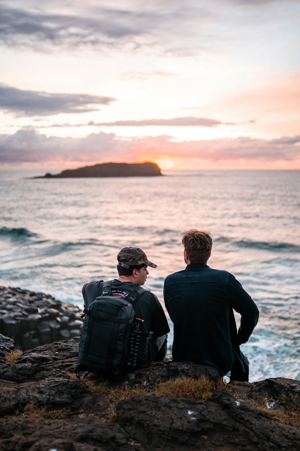 man and woman sitting on rock near sea during daytime